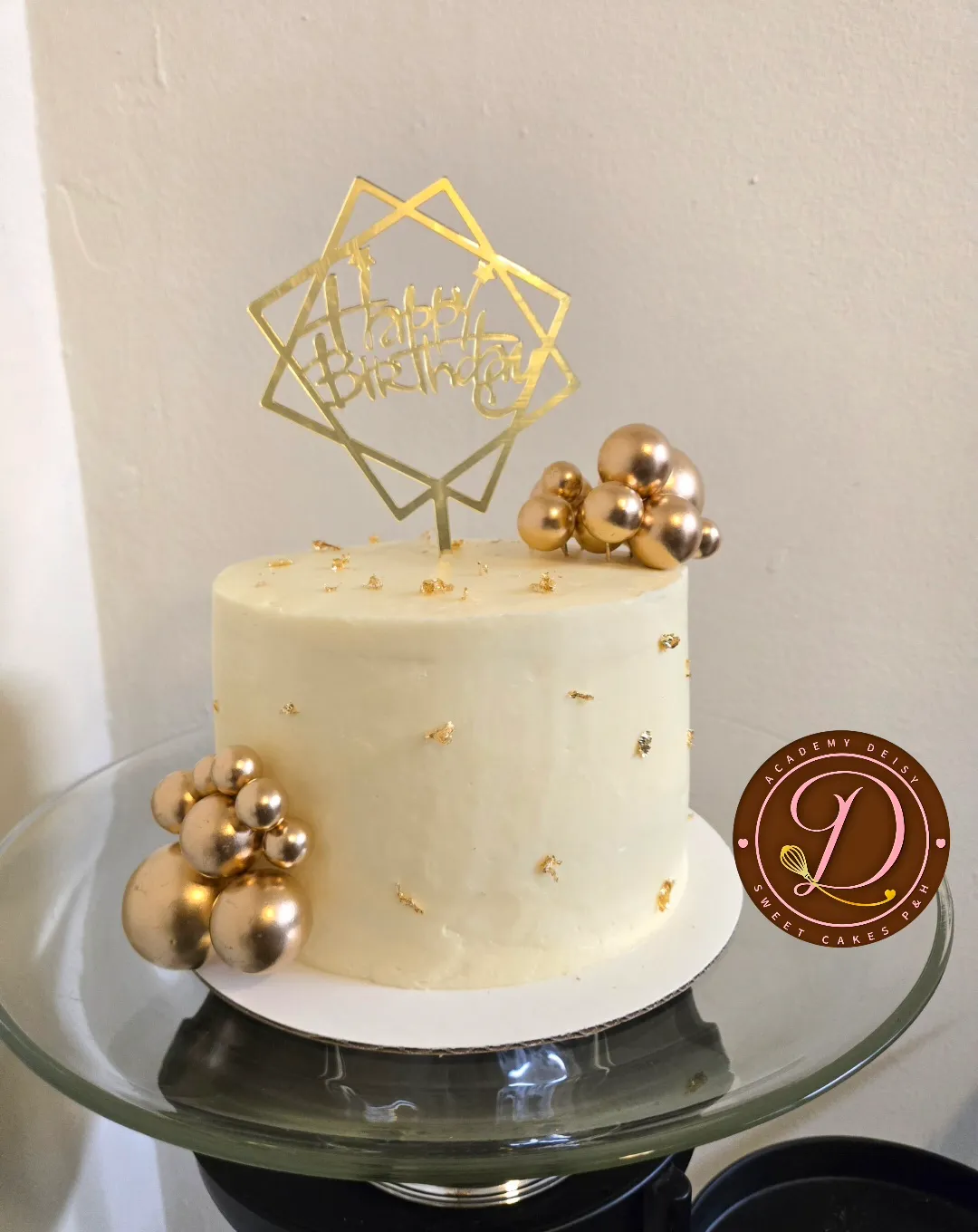 Cake blanco con esferas doradas de chocolate y topper de cumpleaños